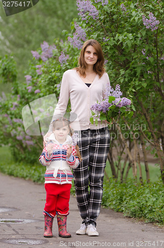 Image of Young woman with a daughter in lilac bush