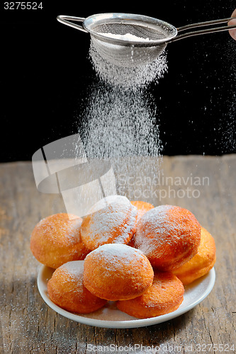 Image of pours sugar over donuts