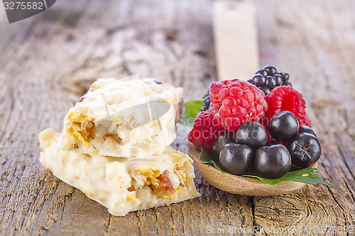 Image of muesli bars with fresh berries in spoon on wooden