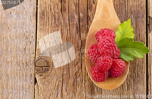 Image of fresh raspberry in wooden spoon on wooden table