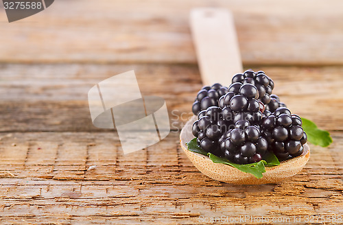 Image of blackberries with spoon on wooden background