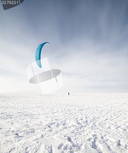 Image of Kiteboarder with blue kite on the snow