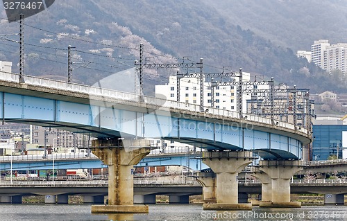 Image of train bridge across river and city background at busan