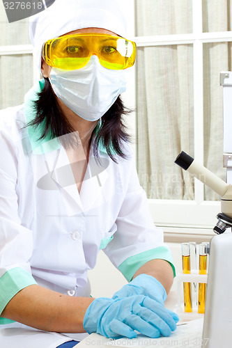 Image of scientist with microscope and computer