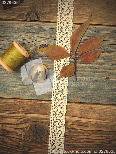 Image of still life with lace ribbon, vintage buttons, spools of thread a