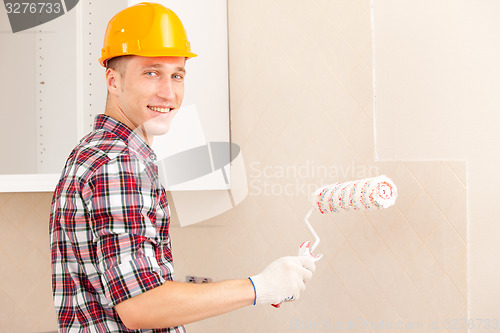 Image of smiling young painter with a roller