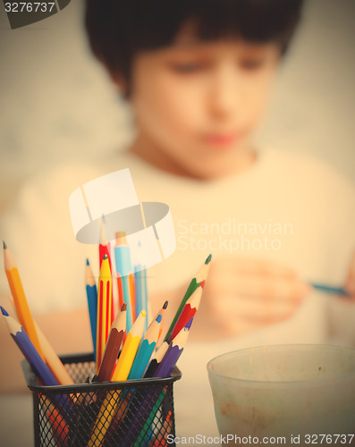 Image of colored pencils for drawing in pencil holders and the child on b