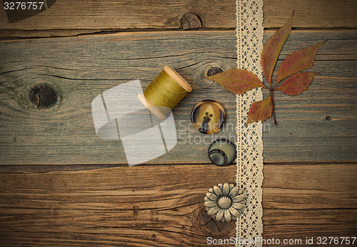 Image of lace ribbon, vintage buttons, spools of thread and dry leaves