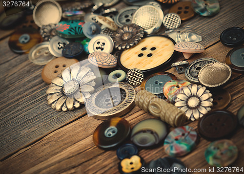 Image of Vintage buttons in large numbers scattered on aged wooden boards