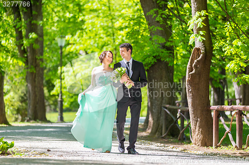 Image of Wedding couple walking in park.