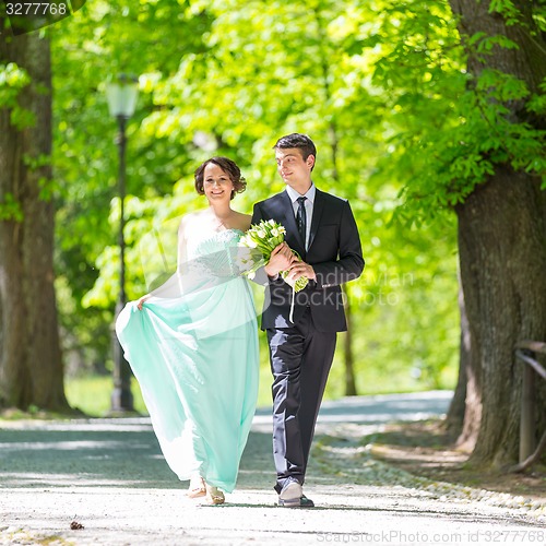 Image of Wedding couple walking in park.