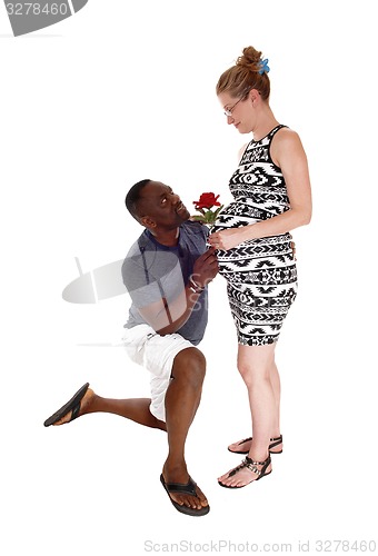 Image of Black man kneeling for white pregnant woman.