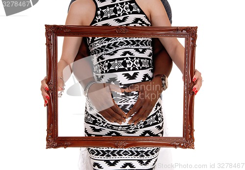 Image of Closeup of pregnant couple with picture frame.