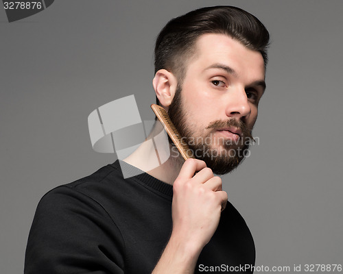 Image of young man comb his beard and moustache 