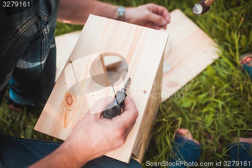 Image of Male hands with wooden birdhouse