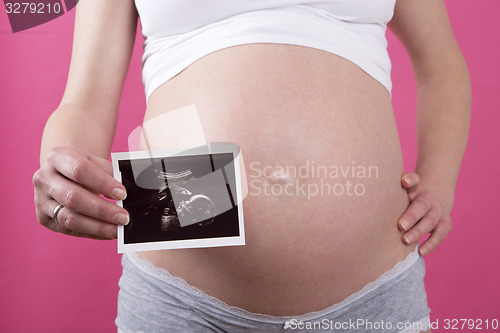 Image of Closeup of a pregnant woman with an ultrasound picture in her ha