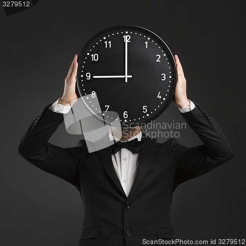 Image of Handsome young man holding a clock
