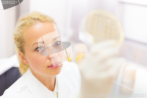 Image of Scientist observing petri dish.