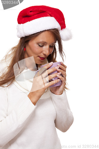Image of Cold young woman in a Santa hat sipping coffee tea