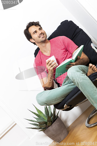 Image of Man Sitting on Chair with Book and a Drink