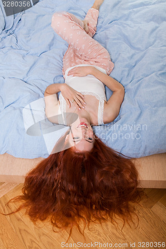 Image of Woman Lying on Bed with Hair Hanging Over the Edge