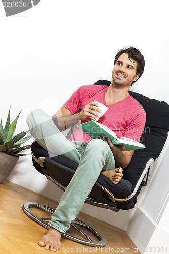 Image of Man Sitting on Chair with Book and a Drink