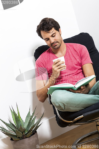 Image of Man Sitting on Chair with Book and a Drink