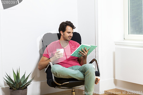 Image of Man Sitting on Chair with Book and a Drink