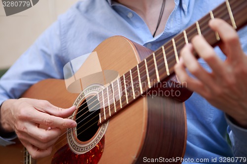 Image of Man playing classic, acoustic guitar