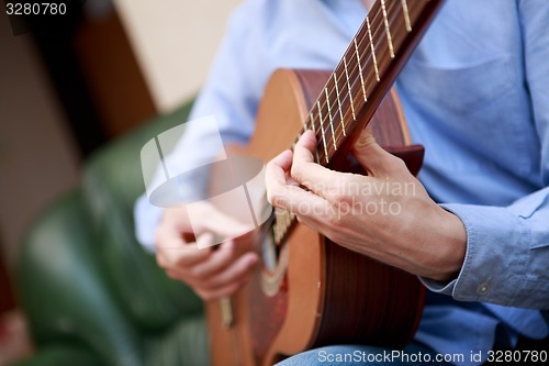 Image of Man playing classic, acoustic guitar