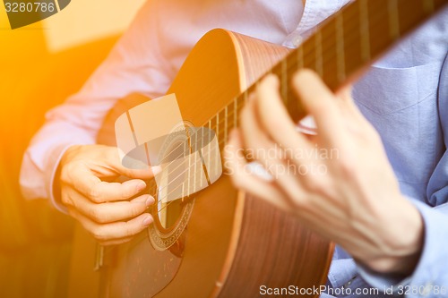 Image of Young musician playing at acoustic guitar