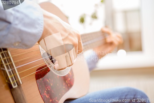 Image of Man playing classic, acoustic guitar