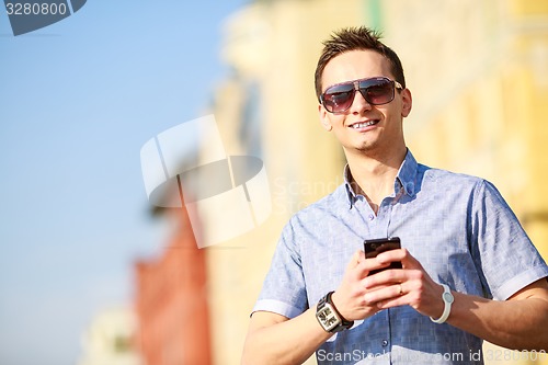 Image of Outdoor portrait of man with mobile phone in the street.