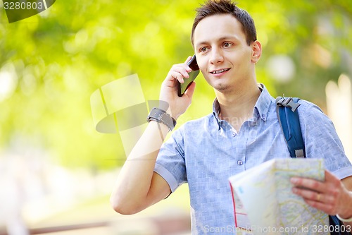 Image of Man holding map outdoors and talking by phone