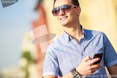 Image of Outdoor portrait of man with mobile phone in the street.