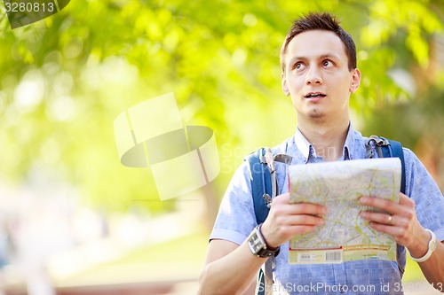 Image of Young man with a map outdoors