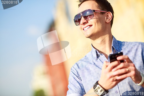 Image of Outdoor portrait of man with mobile phone in the street.