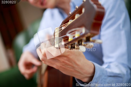 Image of Young musician playing at acoustic guitar