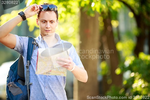 Image of Young man with a map outdoors