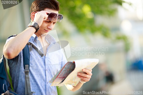 Image of Young man with a map outdoors