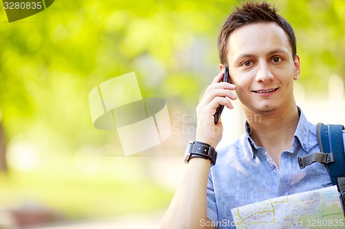 Image of Man holding map outdoors and talking by phone