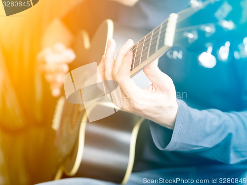 Image of Male hand playing on acoustic guitar. Close-up.