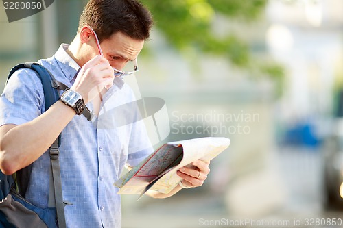 Image of Young man with a map outdoors