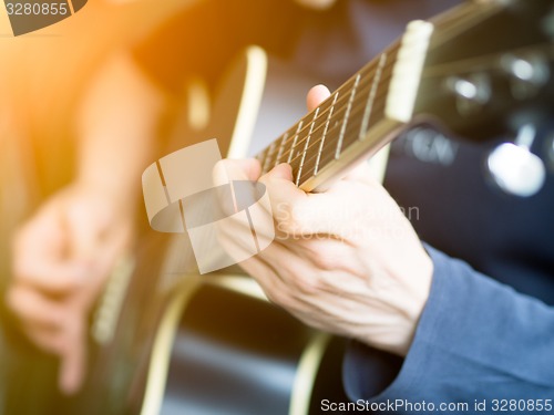 Image of Male hand playing on acoustic guitar. Close-up.