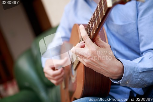 Image of Man playing classic, acoustic guitar