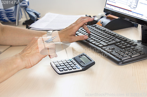 Image of Businesswoman typing on calculator