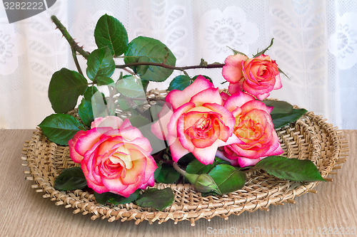 Image of The roses on the table on a wicker platter.