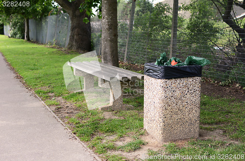 Image of Full trash can next to empty bench