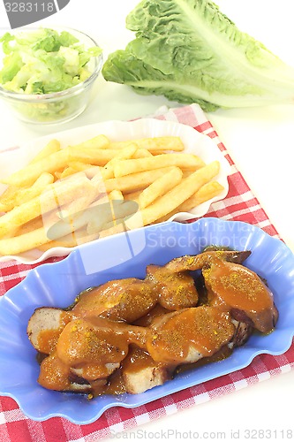 Image of Currywurst with french fries with salad