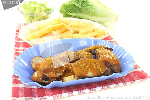 Image of Currywurst with french fries on a napkin